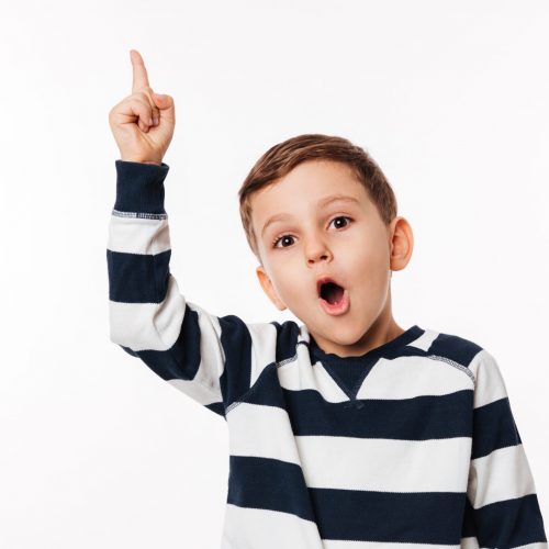 Portrait of an excited smart little kid pointing finger up and looking at camera isolated over white background